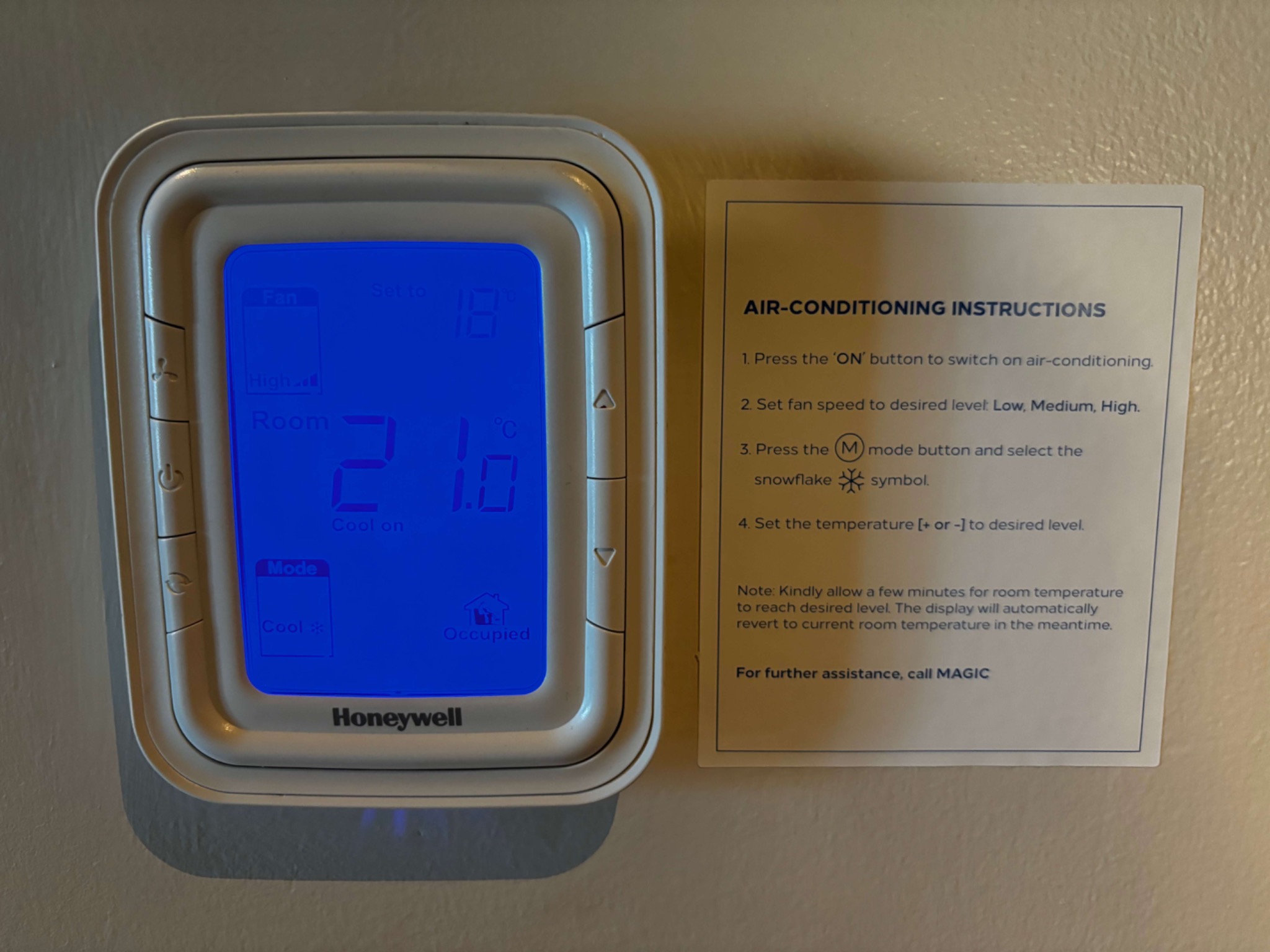 Hotel air-conditioning instruction sign mounted beside room thermostat