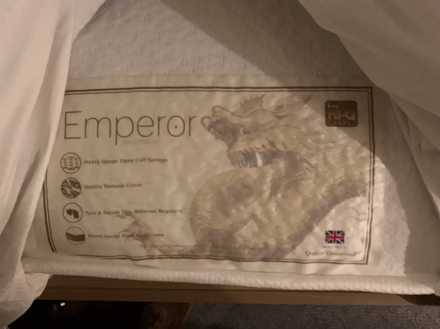 Mattress label visible beneath hotel bedding showing a non-standard supplier product