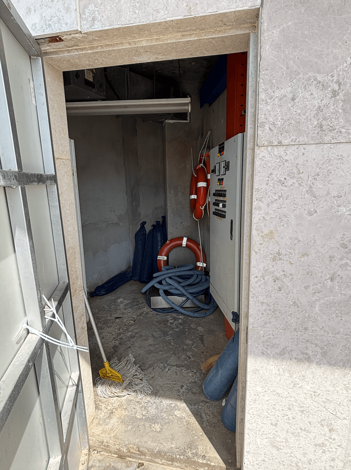 Locked hotel pool safety equipment cupboard with no visible life-saving equipment poolside